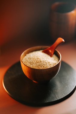 Koyu renkli bir yüzeyde, ahşap bir kasede pişmemiş kuskus.