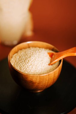 Tahta bir kasede kuskus pişmeye hazır, içinde tahta bir kaşık dinleniyor.