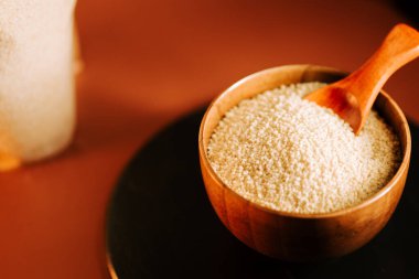 Kuskus ahşap kasede, sıcak bir mutfak ortamında yemek yapmaya hazır.