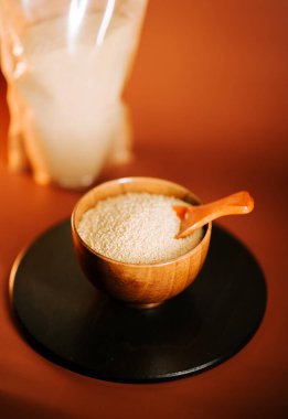 Tahta bir kasede kuskus, karanlık bir yüzeyde kaşıkla, yumuşak bir arka planın yanında.