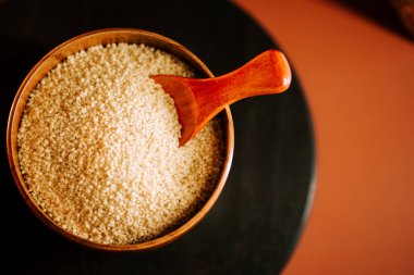 Kuskus ahşap bir kasede, kırsal bir mutfakta kepçeyle.