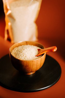 Tahta bir kasede kuskus. Kereste kepçesiyle karanlık bir yüzeye, bir poşetin yanına yerleştirilmiş.