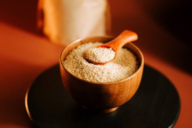 Kuskus ahşap bir kasenin içinde yemek hazırlığı ve pişirmeye hazır bir kaşığın yanında oturur.