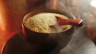 Adding flavor to uncooked couscous in a cozy kitchen setting with steam rising