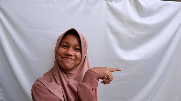 亚洲穆斯林少女 面带微笑 指向空旷的空间 — 图库照片