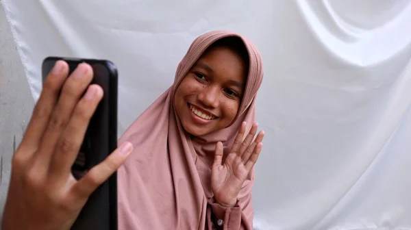 使用智能手机打电话 视频通话的亚洲穆斯林女青年 — 图库照片