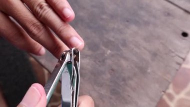 Asyalı bir adamın uzun tırnaklarını kesmesi.