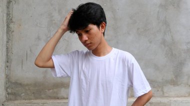 Asyalı adamın başı dönüyor ve kafasını elinde tutuyor.                       