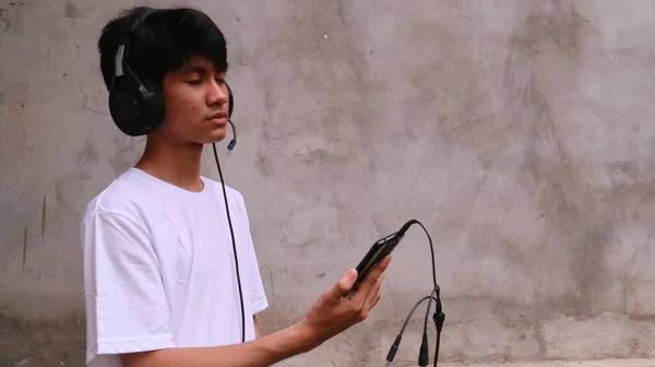 亚洲人正在用智能手机和耳机来听歌曲 — 图库照片