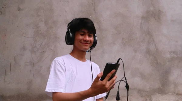 アジア系の男性はスマートフォンやヘッドセットを使って歌を聞き — ストック写真