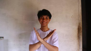 Beyaz tişörtlü Asyalı bir adam çapraz kol hareketi yapıyor. Jestlere hayır de.                        