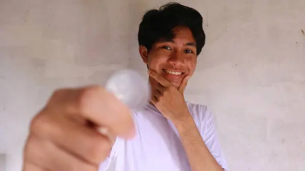 一个穿着白色T恤的亚洲人拿着并展示着印尼盾币 — 图库照片