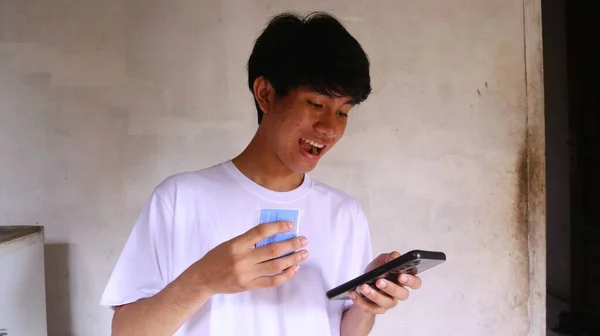 一个亚洲人正在用他所持有的卡和智能手机进行支付交易 — 图库照片