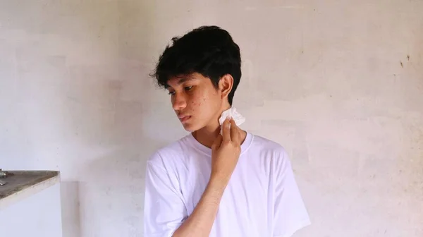 一个穿着白色T恤的亚洲人正在用纸巾擦拭他的脸 — 图库照片