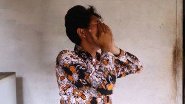 Tipik Endonezya Batik giysileri giyen Asyalı bir adamın ifadesi.        