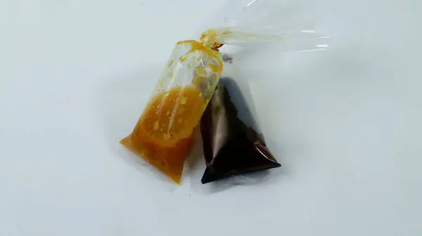 one packet of soy sauce and chili sauce on a white background