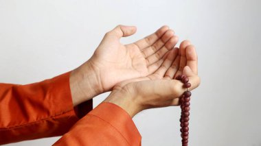 Asyalı Müslüman adamın elleri beyaz arka planda dua ediyor.