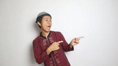 heyecanlı Asyalı Müslüman adam beyaz arkaplanı işaret ediyor.