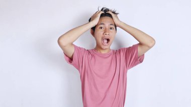 Kafasını tutarken şok olmuş Asyalı bir adam.