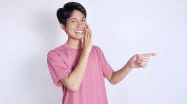 Asyalı bir adam heyecanlı bir hareketle beyaz arka planda fotokopi alanının kenarını işaret ediyor.