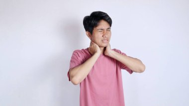 Asyalı bir adam boynunu tutuyor çünkü beyaz bir arka planda boynu ağrıyor.