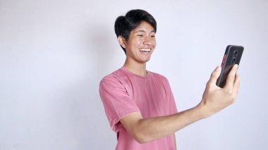 Beyaz arka planda akıllı telefonu tutan heyecanlı Asyalı adam.