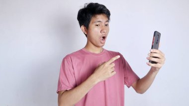 Asyalı bir adam beyaz arka planda jest yaparak ve akıllı telefon tutarak şoka girdi.