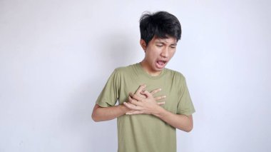 Göğüs ağrısı çeken Asyalı bir adam göğsünün sağ tarafını tutuyor ve beyaz bir arka planı var.