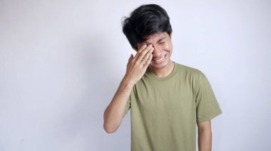 Yakışıklı genç Asyalı gözlerini izole edilmiş beyaz bir arka plana sürtüyor.