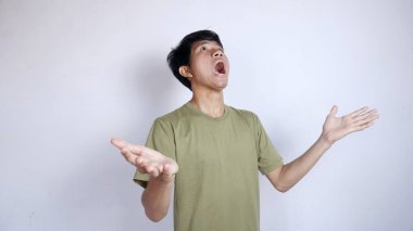 Şok olmuş genç bir Asyalı, iki eli de yukarıda, izole edilmiş beyaz bir arka plana bakıyor.