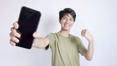 Akıllı telefon gösteren heyecanlı Asyalı adam beyaz arka planda izole edilmiş. Kazan ve başarılı ol.