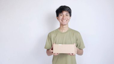 Gülümseyen Asyalı adam, elinde tuttuğu paketi izole edilmiş beyaz bir arka planda gösteriyor.