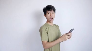 Asyalı bir adamın izole edilmiş beyaz arka planda akıllı telefonuyla oynamasına şaşırdım.