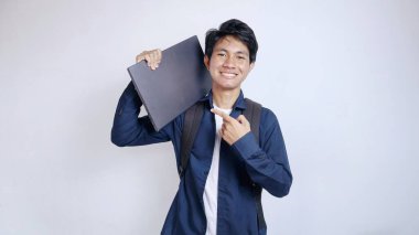 Asyalı genç ve yakışıklı bir erkek öğrenci dizüstü bilgisayarı olduğu için mutlu, izole edilmiş beyaz bir geçmişi var, okula geri dönüyor.