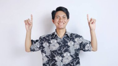 Batik bez giyen yakışıklı Asyalı heyecanlı genç adam izole edilmiş beyaz bir arka planda yukarı doğru hareket ediyor.