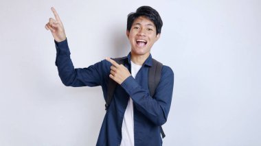 Yakışıklı Asyalı genç bir adam, hevesli bir öğrenci, izole edilmiş beyaz bir arka plana işaret eden hareketler.