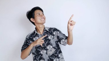 Batik bez giyen yakışıklı Asyalı heyecanlı genç adam izole edilmiş beyaz bir arka planda yukarı doğru hareket ediyor.