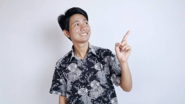 Batik bez giyen yakışıklı Asyalı heyecanlı genç adam izole edilmiş beyaz bir arka planda yukarı doğru hareket ediyor.