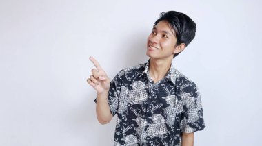 Batik bez giyen yakışıklı Asyalı heyecanlı genç adam izole edilmiş beyaz bir arka planda yukarı doğru hareket ediyor.