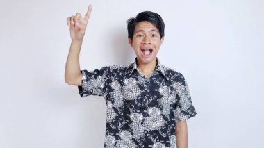 Batik bez giyen yakışıklı Asyalı heyecanlı genç adam izole edilmiş beyaz bir arka planda yukarı doğru hareket ediyor.