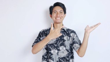 Batik jestler yapmış yakışıklı bir Asyalı. Eli avucunun içinde, izole edilmiş beyaz bir arka planı işaret ediyor.