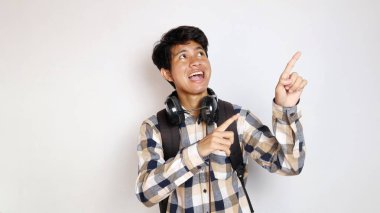 Mutlu Asyalı genç bir adam iki eliyle beyaz arka planda poz veriyor.