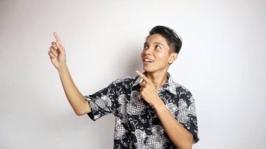 Batik tişört giyen yakışıklı genç adam açık fotokopi alanının tepesine izole edilmiş beyaz bir arka planı olan poz veriyor.