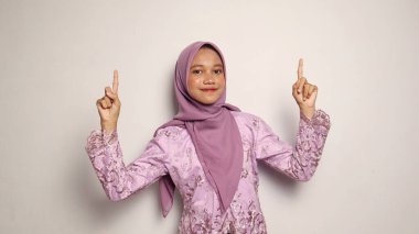 Gülümseyen Endonezyalı genç kızlar kebaya giyer ve tesettürlü poz verir.