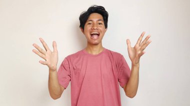 Genç yakışıklı Asyalı adam mutlu, neşeli ve heyecanlı poz veriyor. Vay canına ve yalnız beyaz bir geçmişi var. Kırmızı bir gömlek giyiyor.