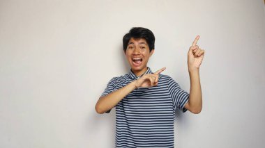 Yakışıklı Asyalı genç adam izole edilmiş beyaz bir arkaplanı işaret ediyor.