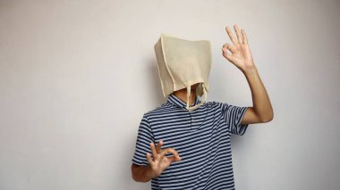 Kafasında alışveriş torbası olan genç Asyalı bir adam. El hareketlerinde sorun yok, beyaz bir geçmişi var.