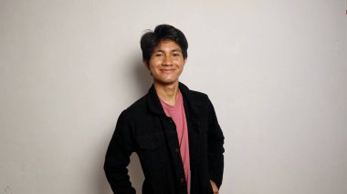 Yakışıklı Asyalı adam gülümsüyor ve mutlu, havalı siyah bir ceket giyiyor, rahat, karizmatik, izole beyaz bir arka planda kameraya bakıyor.