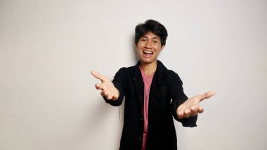 Asyalı yakışıklı, soyutlanmış beyaz arka planda genç bir adam davet ediyor. Gelmene sevindim.