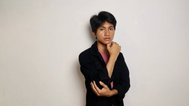 Yakışıklı Asyalı adam gülümsüyor ve mutlu, havalı siyah bir ceket giyiyor, rahat, karizmatik, izole beyaz bir arka planda kameraya bakıyor.